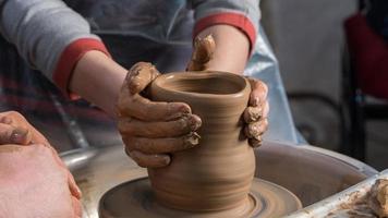 Teaching pottery to children. The teacher gives a master class in modeling photo
