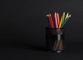 set of colored pencils in a basket on a black background, isolated. back to school photo