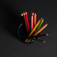 set of colored pencils in a basket on a black background, isolated. back to school photo
