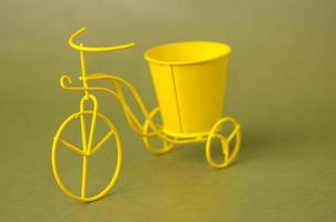 Bicicleta metálica de juguete de recuerdo con un balde sobre un fondo verde oscuro