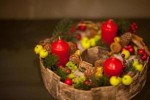 red Christmas candle in a basket with berries and fir cones with green apples photo