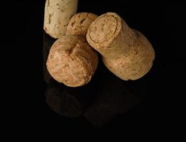 Heap of old wine corks on black background with reflection