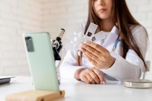 Mujer joven médico o científico que usa microscopio, que tiene llamadas en línea que muestran muestras, que enseñan en línea foto