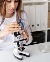 Young doctor or scientist woman using microscope photo
