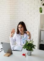 Young doctor woman having online call or consulting, doctor working online from home photo