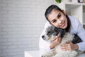 Veterinario sonriente examinando y abrazando perro de raza mixta