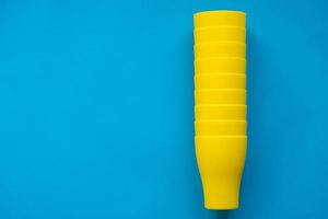 Many blue paper disposable cups on yellow background. Set for party photo