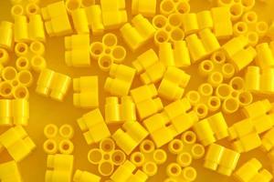 bloques de construcción de plástico amarillo sobre fondo amarillo. Fondo de bloques de construcción de detalles de plástico.