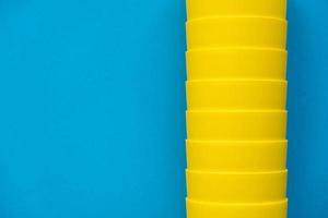 Many blue paper disposable cups on yellow background photo