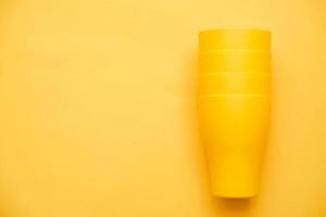 Yellow plastic cups and on yellow background. Cooking utensil photo