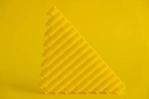 Yellow plastic building blocks in shape of a pyramid on yellow background photo