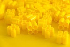 Yellow plastic building blocks on yellow background. Background of plastic details building blocks photo
