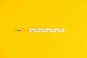 Medical mercury thermometer on a yellow background photo