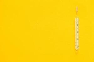 Medical mercury thermometer on a yellow background photo