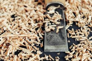 Chisel with wooden shavings on black background. Old woodworking hand tool photo