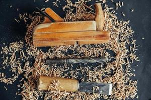 Old hand plane, drill and chisel with wooden shavings on black background. Old woodworking hand tool photo