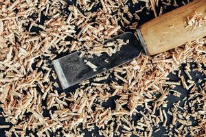 Chisel with wooden shavings on black background. Old woodworking hand tool photo