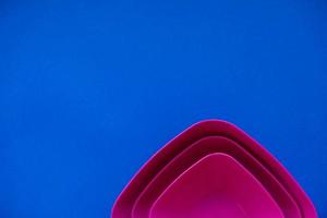 Set of pink plates on blue background. Plastic utensils for the kitchen photo