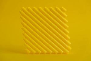 Yellow plastic building blocks in shape of a cube on yellow background photo