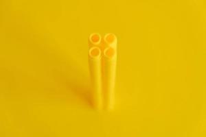 Yellow plastic building blocks in shape of a tower on yellow background. Background of plastic details building blocks photo