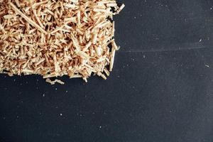 Wood shavings on black background. Background of fresh wood shavings. Copy, empty space for text photo