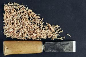 Chisel with wooden shavings on black background photo