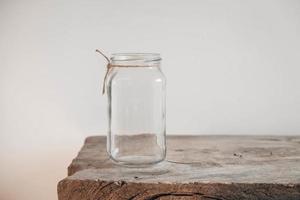 Glass transparent jar on wooden table on white wall background photo