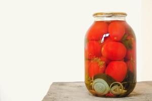 Pickled tomato in a glass jars on wooden table