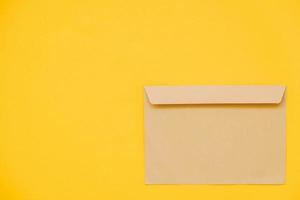 Kraft paper envelope on a yellow background. Perfect for invitations, card, message decorations photo