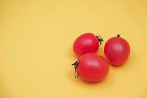 Red tomatos vegetable on a yellow background photo