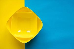 Empty yellow bowls on on blue and yellow background. Plastic utensils for the kitchen photo