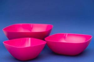 conjunto de placas de color rosa sobre fondo azul. utensilios de plastico para la cocina foto