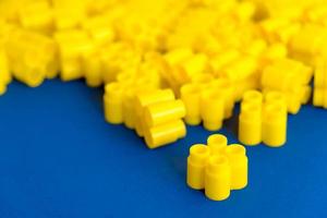 Yellow plastic building blocks on a blue background. Pieces and elements of constructor. Parts of bright small spare parts for toys photo