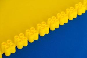 Yellow plastic building blocks on blue and yellow background photo