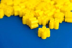 bloques de construcción de plástico amarillo sobre un fondo azul. piezas y elementos de constructor foto