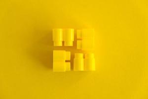Yellow plastic building blocks on yellow background photo