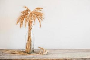 Wheat ears in a glass vase on a wooden table photo