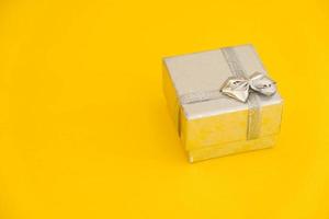 caja de regalo plateada sobre fondo amarillo foto