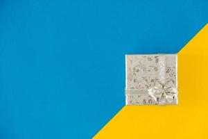 Silver gift box on blue and yellow background photo