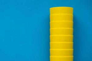 Many yellow plastic cups on blue background. Set for party photo