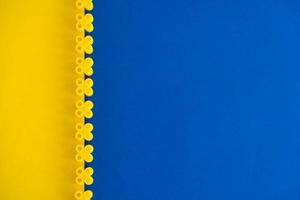 Yellow plastic building blocks on blue and yellow background. Pieces and elements of constructor photo