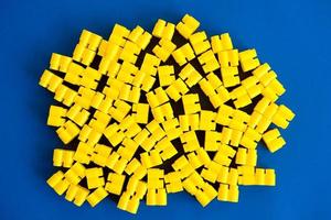 Yellow plastic building blocks on a blue background photo