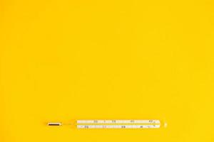 Termómetro de mercurio médico sobre un fondo amarillo foto