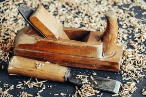 Old hand plane and chisel with wooden shavings on black background. Old woodworking hand tool photo