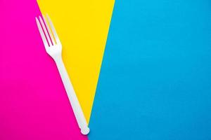 Plastic white fork on multicolored background. Cooking utensil photo