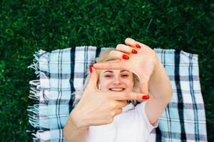 Woman smiling making frame with hands and fingers with happy face lying on rug green background photo