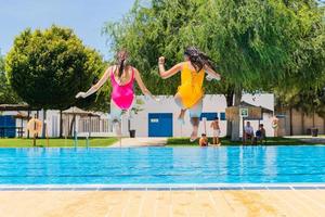 dos adolescentes saltando en una piscina. dos niñas saltando a una piscina foto