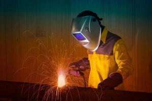 Industrial Worker with safety equipments and protective mask welding steel structure in construction factory. photo