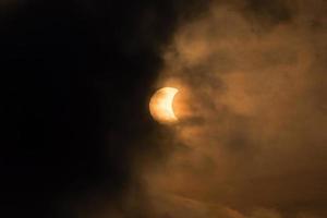 la luna cubriendo el sol en un eclipse parcial con nubes dramáticas. antecedentes científicos, fenómeno astronómico foto