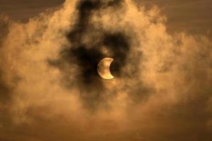 The Moon covering the Sun in a partial eclipse with dramatic cloud. Scientific background, astronomical phenomenon. photo